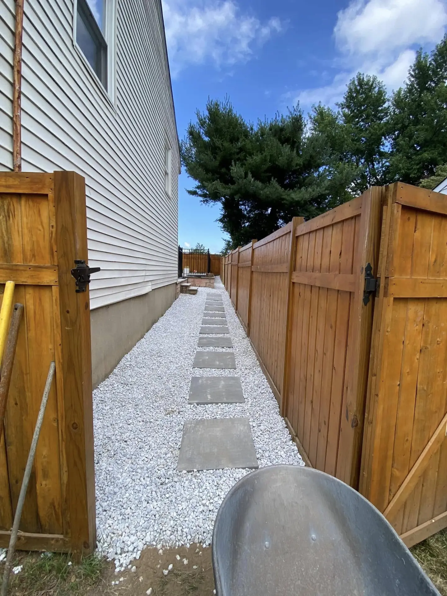 Stepping stone path set in white gravel between a home and fence