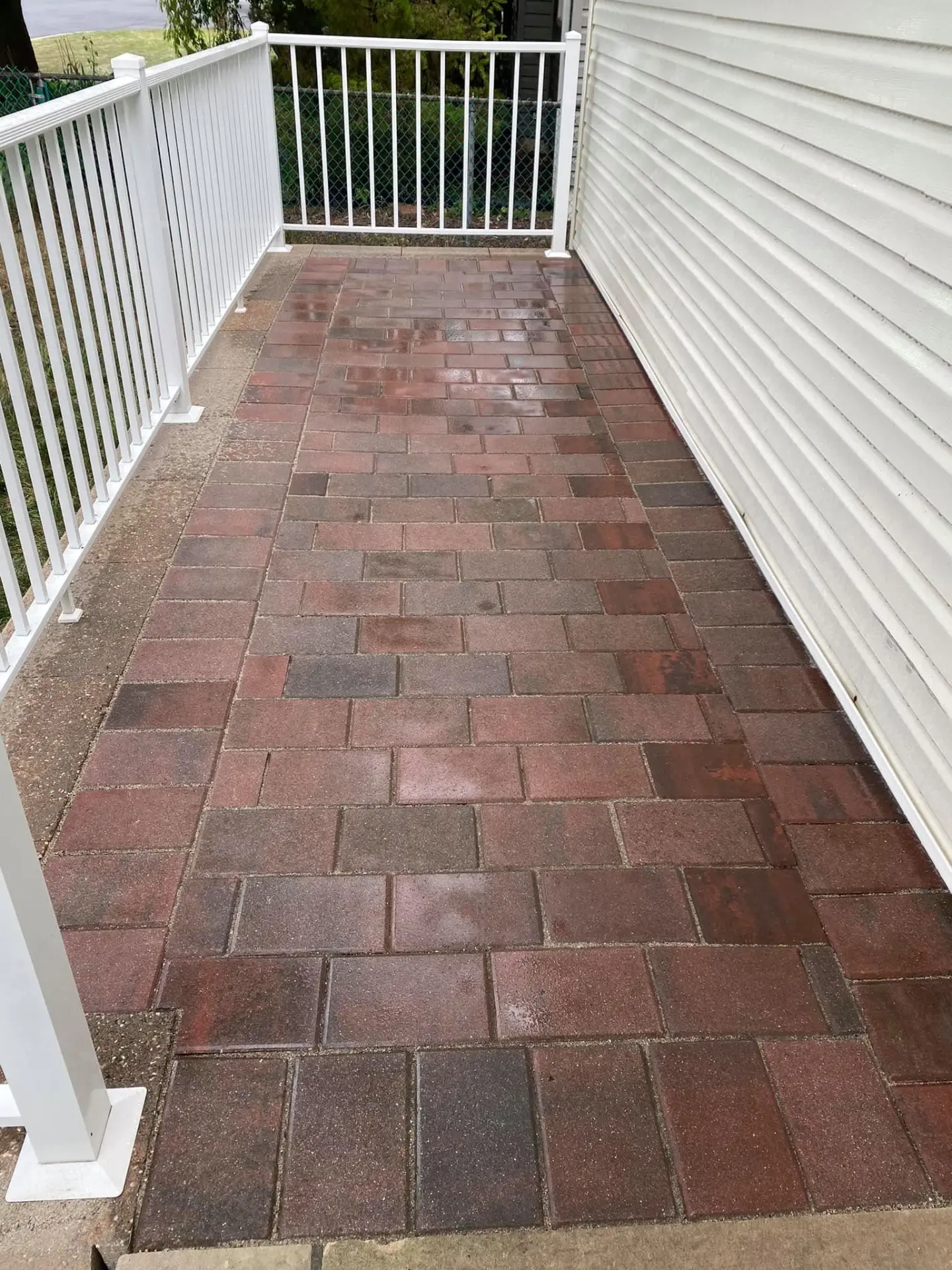 Brick paver porch and walkway alongside a home with white railings